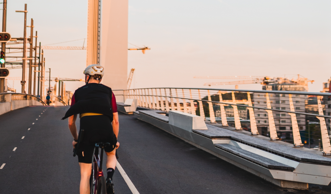 A cyclist riding over a Gothenburg bridge at sunset