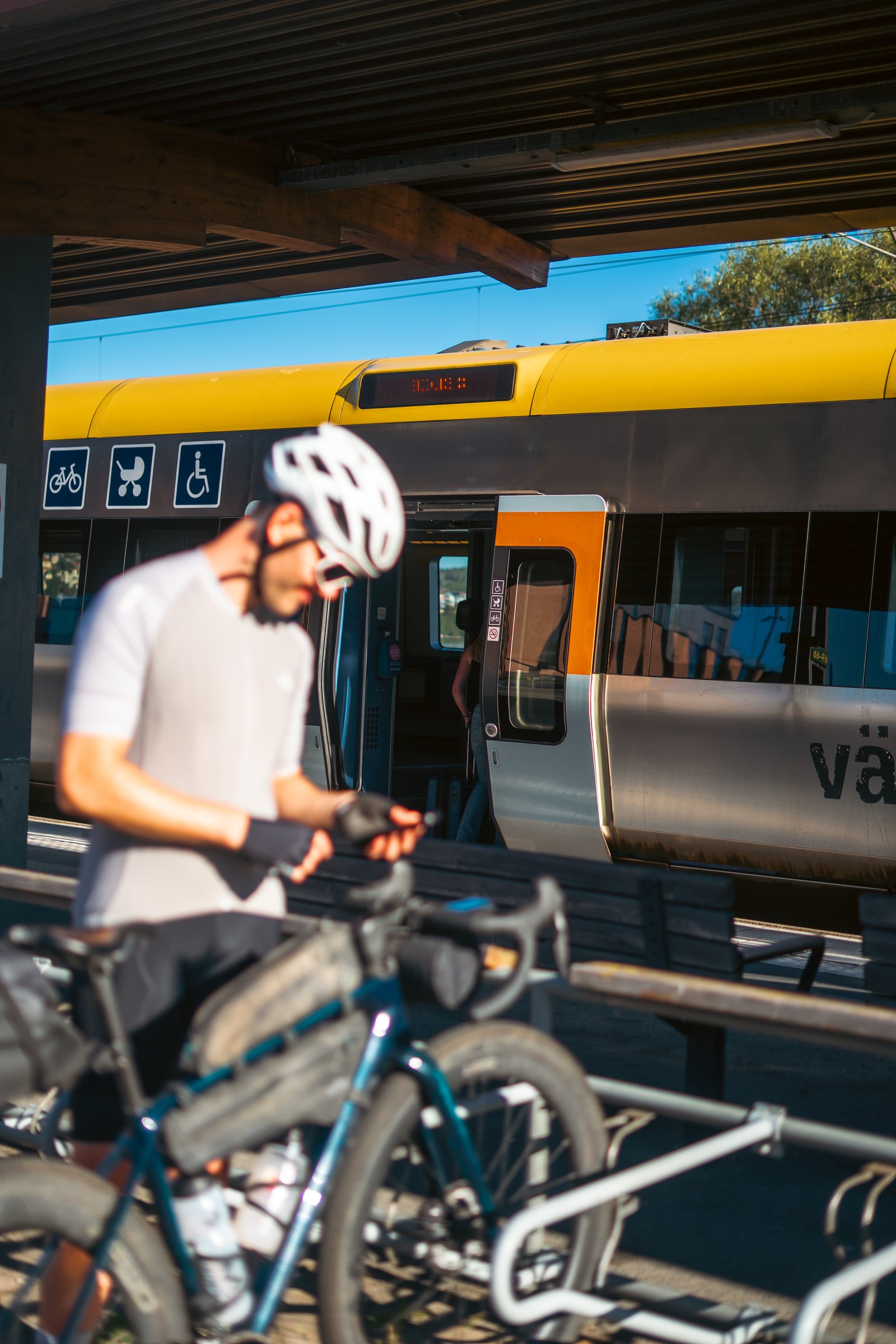 Cyclist checking his phone next to his loaded bike beside a regional train
