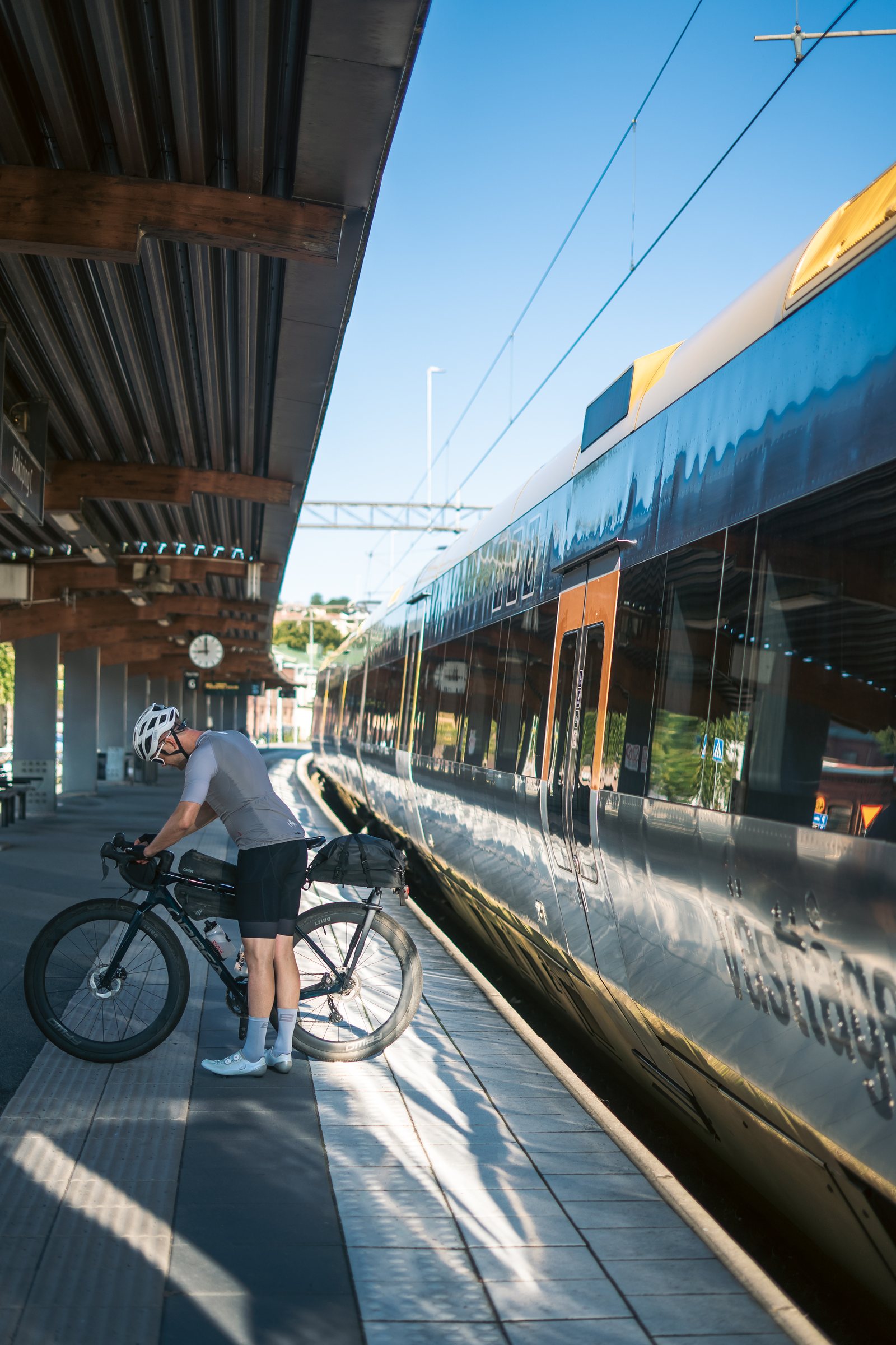 Cyclist adjusting his bike on the platform beside a regional train in Jönköping