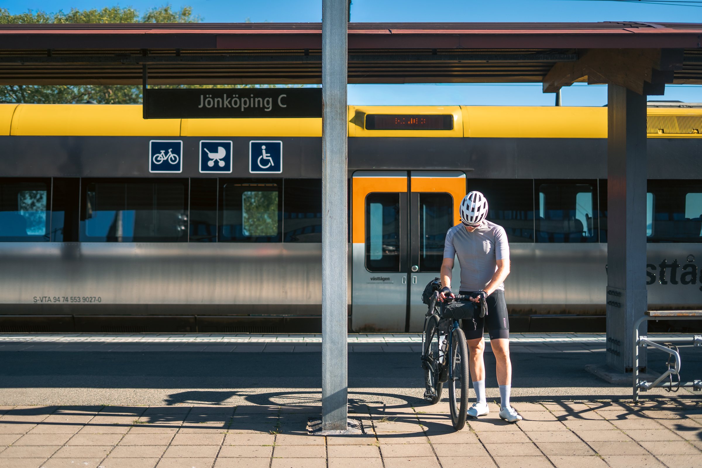 Cyclist with his loaded gravel bike in front of a regional train at Jönköping C