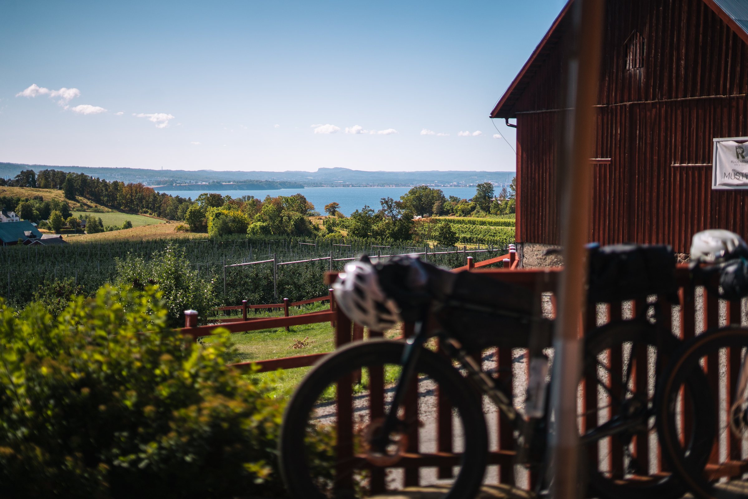 Gravel bikes by a red barn at Rudenstams, orchards and Lake Vättern below