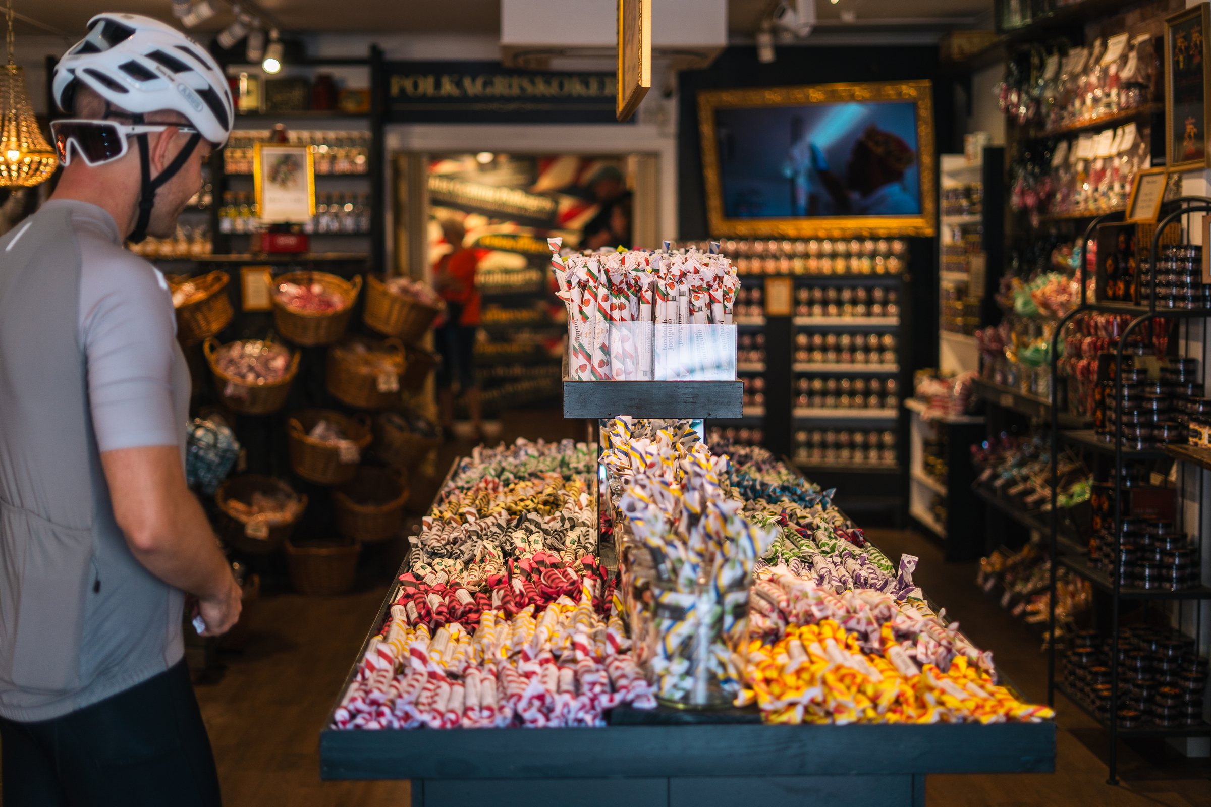 Cyclist looking at a table of polkagris in a candy shop in Gränna
