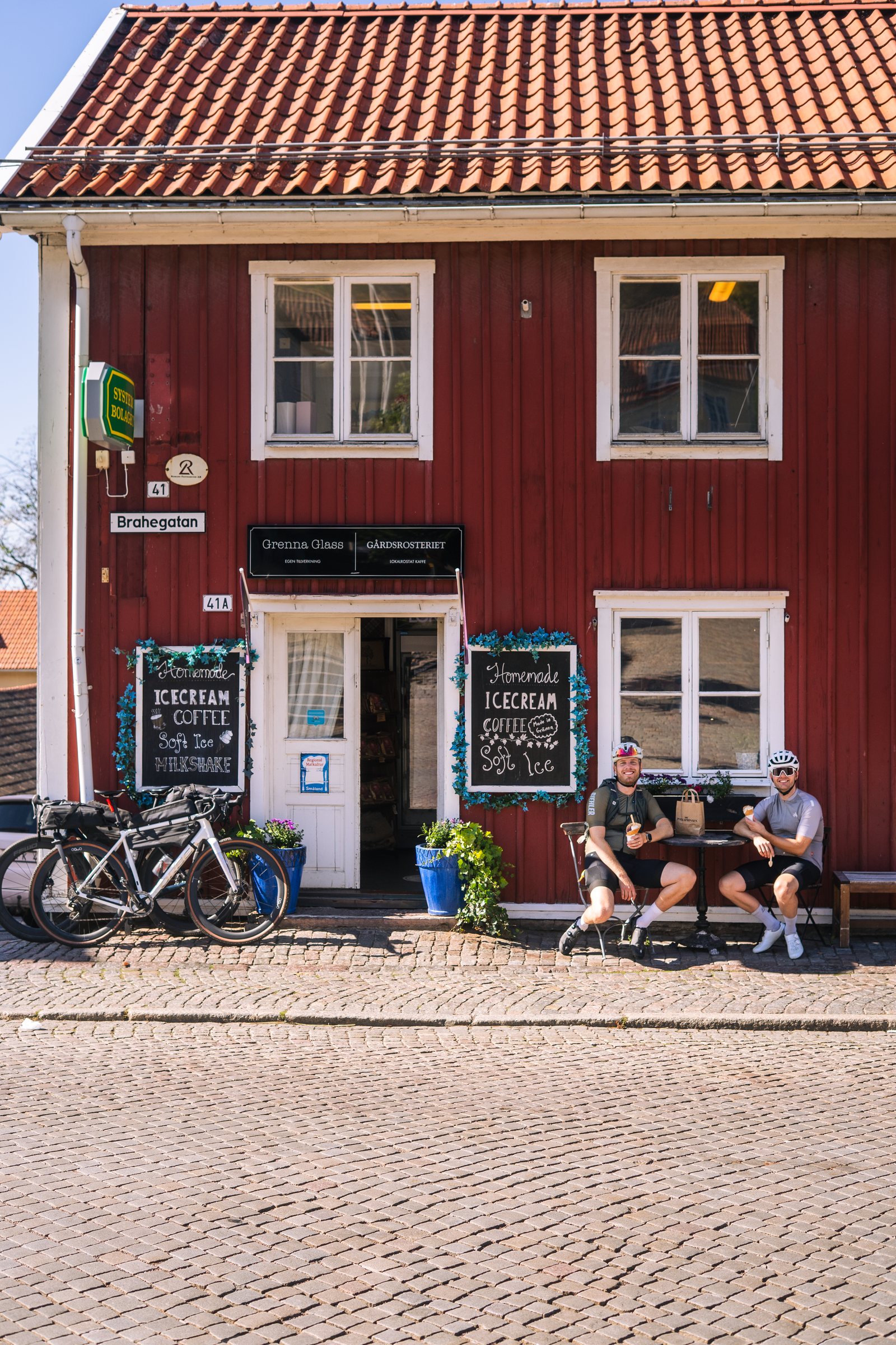 Red wooden ice cream shop on a cobbled square in Gränna, bikes parked outside