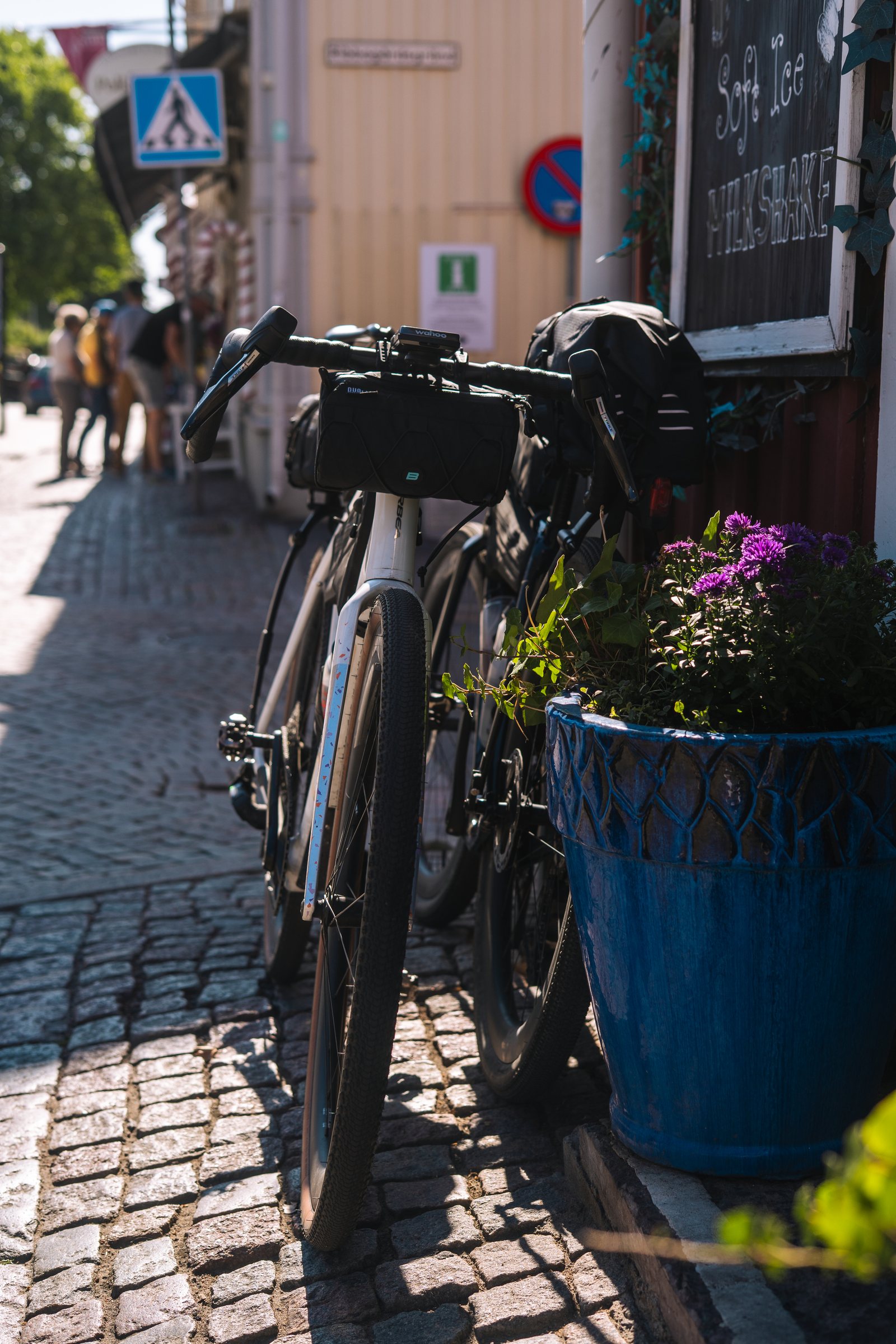 Loaded gravel bike leaning against a flower pot on the cobbles in Gränna