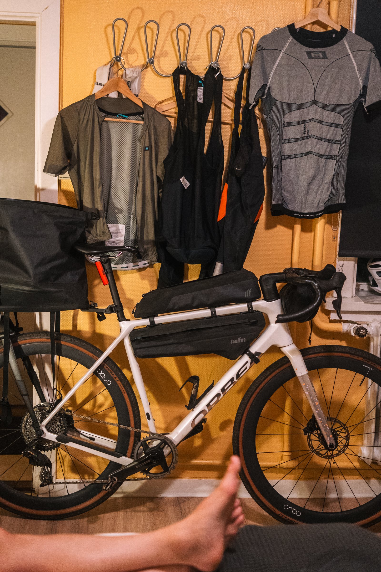Loaded gravel bike and cycling kit hanging on a wall indoors