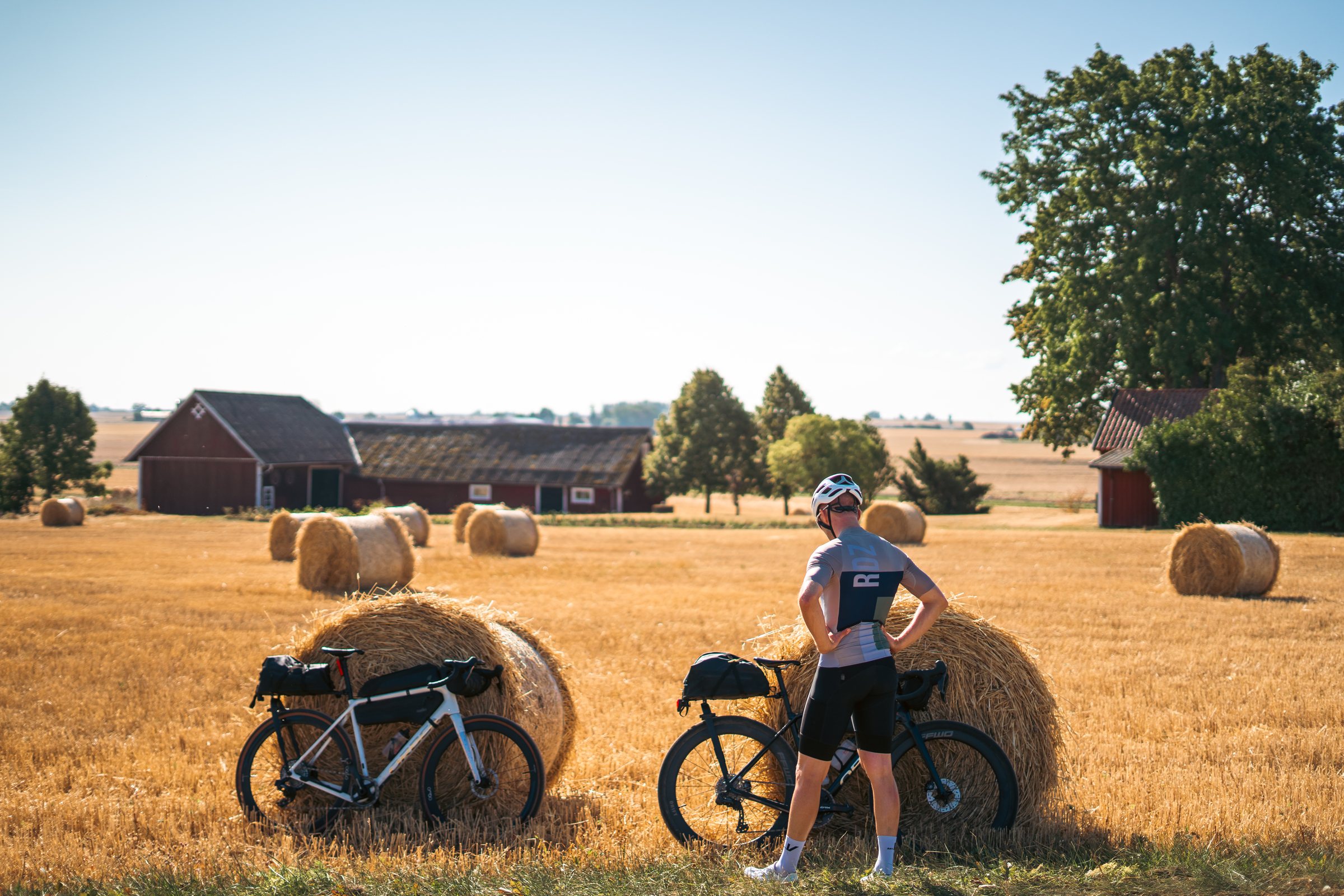 Cyclist and two loaded gravel bikes leaning on hay bales in a harvested field
