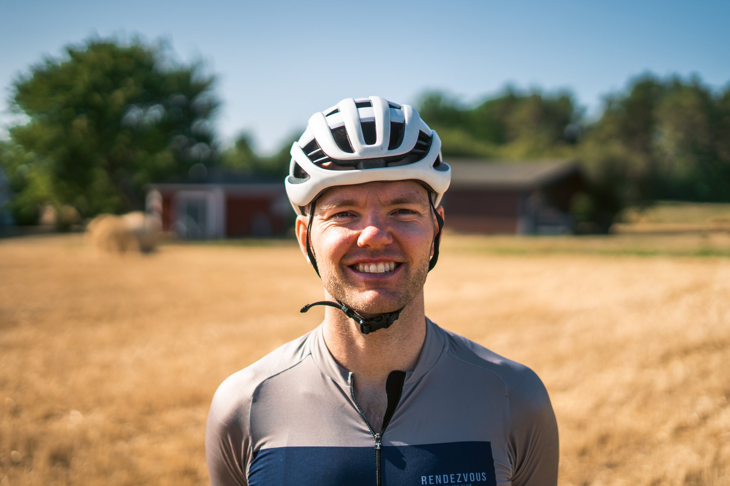 Smiling cyclist in a helmet in front of a harvested field