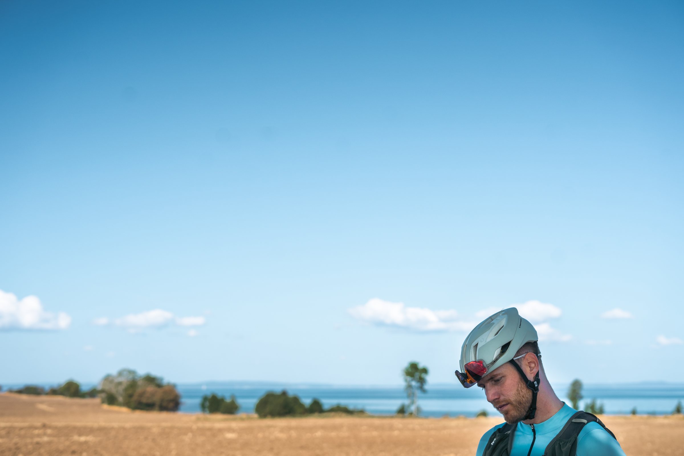 Cyclist looking down, Lake Vättern and flat fields behind