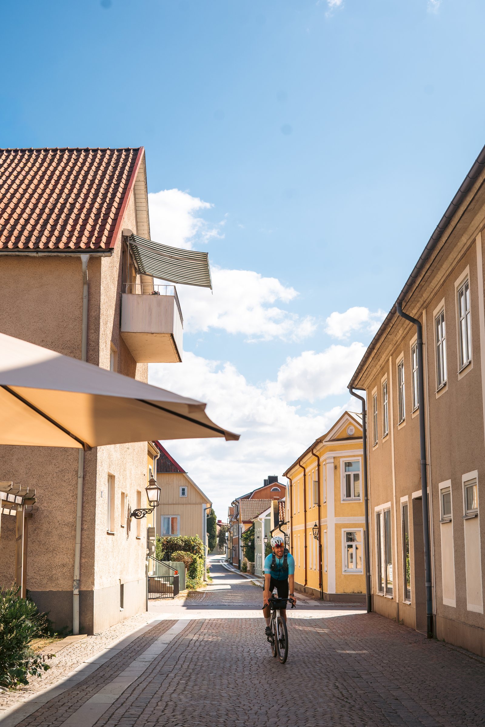 Cyclist riding down a narrow street of old houses in Vadstena
