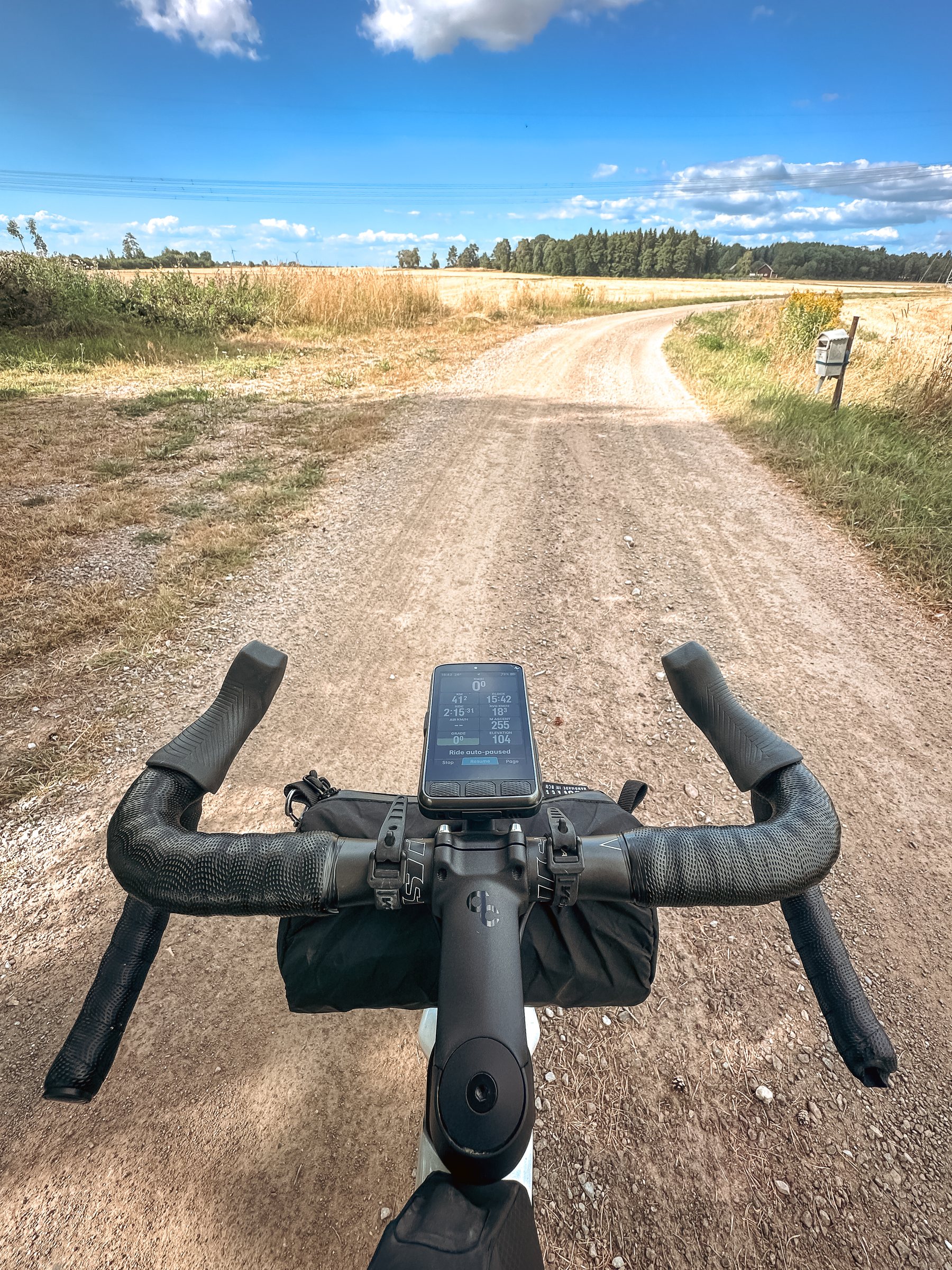 Gravel road through dry fields seen over the handlebars